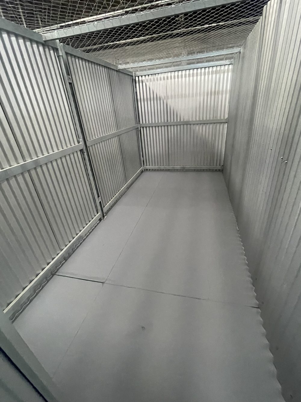 Box vazio da GuardaFácil Box, com piso liso, paredes metálicas e tela de proteção no teto
